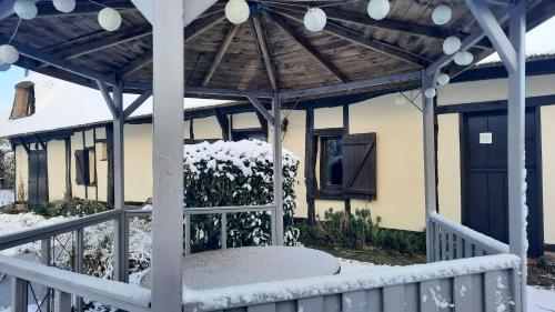 a porch with a pergola in the snow at Les 2 chaumières avec piscine in Épinay