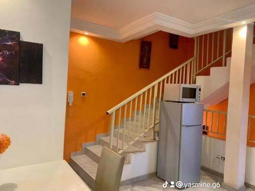 a room with a staircase with a microwave on a refrigerator at RÉSIDENCES ORI in Cotonou