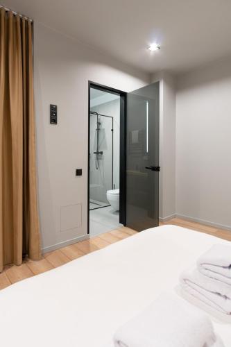 a white bedroom with a mirror and a bathroom at SAVOIE Apartments Bukovel in Bukovel