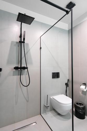 a bathroom with a toilet and a glass shower stall at SAVOIE Apartments Bukovel in Bukovel