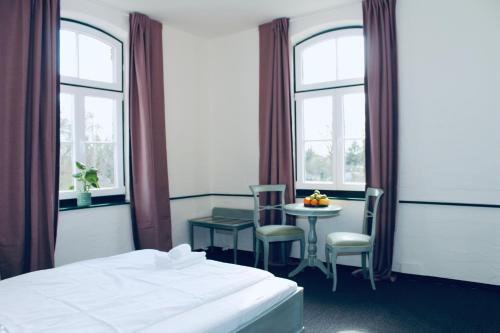 a hotel room with a bed and a table and windows at FREVOR Hotel & Restaurant Alte Wassermühle Lenzen Elbe in Lenzen