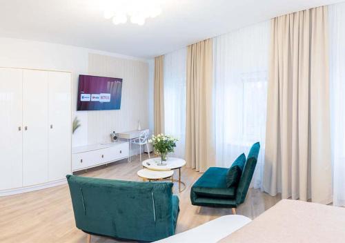 a living room with a green chair and a table at Atostogų Parkas Hotel in Palanga