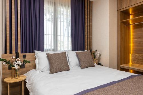 a bedroom with a large white bed with purple curtains at Ema Houses in Antalya