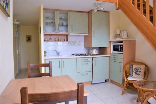une cuisine avec des armoires blanches et une table et des chaises dans l'établissement Appartement avec terrasse VUE SUR MER plage du Coz-Pors à TREGASTEL - Réf 726, à Trégastel