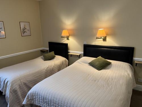 2 camas en una habitación con sábanas blancas y almohadas verdes en Royal Oak Hotel, Garstang, en Garstang