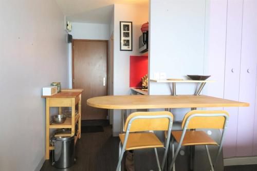 une petite cuisine avec une table et des chaises en bois dans l'établissement Studio VUE SUR MER sur la plage de Trestrignel à PERROS-GUIREC - Réf 833, à Perros-Guirec