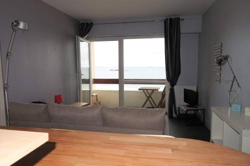 un salon avec un canapé et une grande fenêtre dans l'établissement Studio VUE SUR MER sur la plage de Trestrignel à PERROS-GUIREC - Réf 833, à Perros-Guirec