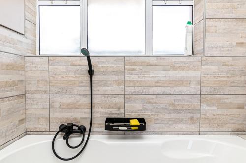 a shower in a bathroom with a black hose at Amanzi402 Oceanview Retreat in Amanzimtoti