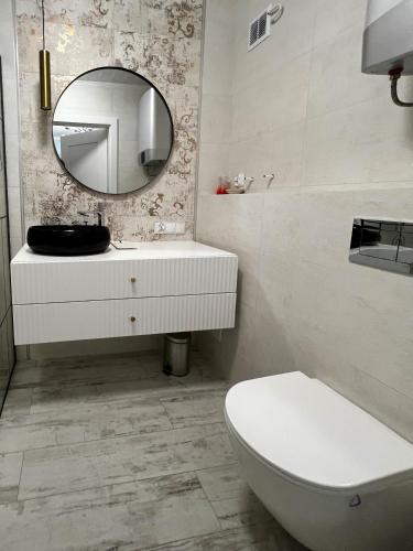 a bathroom with a white toilet and a mirror at PaVoni Terazze Verdi Łeba in Łeba