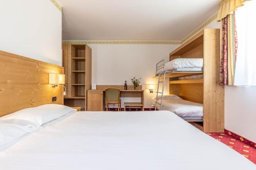 a bedroom with two bunk beds and a desk at Hotel Plank in San Martino di Castrozza
