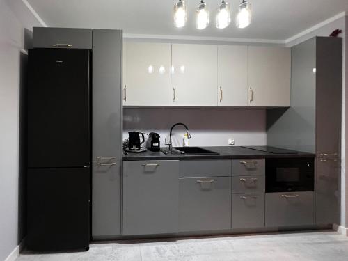 a kitchen with white cabinets and a black refrigerator at PaVoni Terazze Verdi Łeba in Łeba