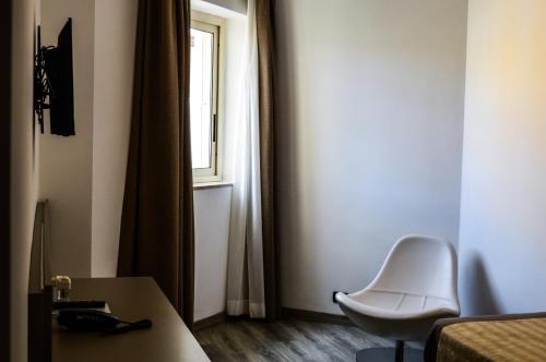 サレルノにあるメディテレニア ホテル ＆ コンベンション センターの白い椅子と窓が備わる客室です。