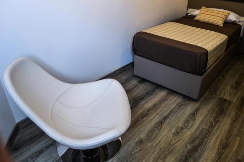 a bedroom with a bed and a white chair at Mediterranea Hotel & Convention Center in Salerno