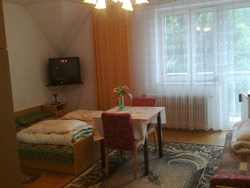 - un salon avec une table et une télévision dans l'établissement Maxim Pokoje Gościnne, à Iwonicz-Zdrój
