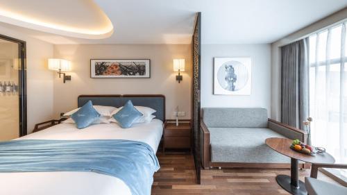 a hotel room with a bed and a chair at Pagoda Hotel Hangzhou West Lake Wulin - City Center and Family Friendly in Hangzhou