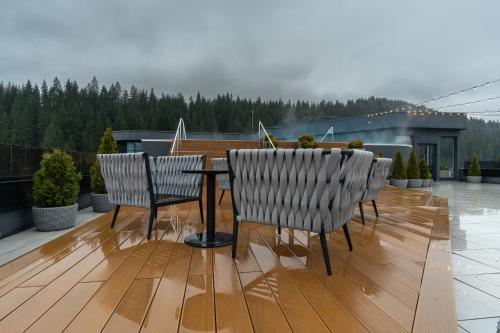two chairs and a table on a deck with ainion at SAVOIE Apartments Bukovel in Bukovel