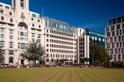 um grande edifício com um campo de relva em frente em Montcalm Royal London House, London City em Londres