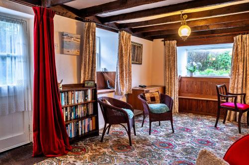 ein Wohnzimmer mit Stühlen und einem Bücherregal mit Büchern in der Unterkunft Finest Retreats - Lewcott in Sennen