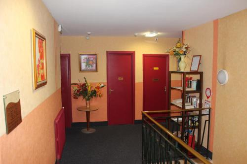 a hallway with two red doors and a shelf with flowers at Hotel Bristol in Châlons-en-Champagne