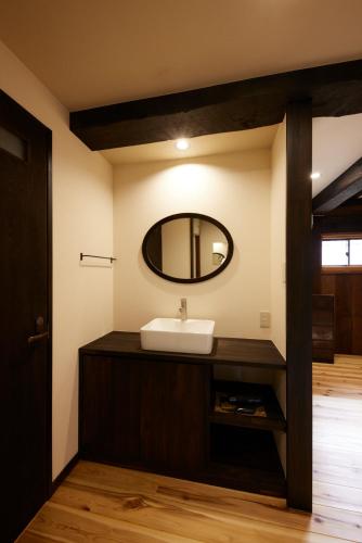 a bathroom with a sink and a mirror at ゲストハウス長閑 in Toyooka