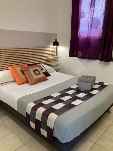 une chambre avec un grand lit avec des oreillers colorés dans l'établissement Maison à 5min à pied du centre ville de porto -vecchio, à Porto-Vecchio