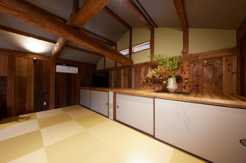 cocina grande con armarios blancos y paredes de madera en ゲストハウス長閑, en Toyooka