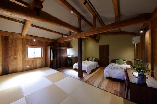 a large room with two beds and wooden ceilings at ゲストハウス長閑 in Toyooka
