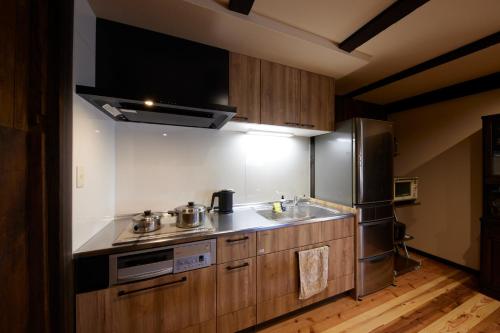 a kitchen with a sink and a stainless steel refrigerator at ゲストハウス長閑 in Toyooka