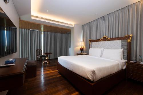a bedroom with a large white bed and a desk and a desk at Novotel Hyderabad Airport in Hyderabad