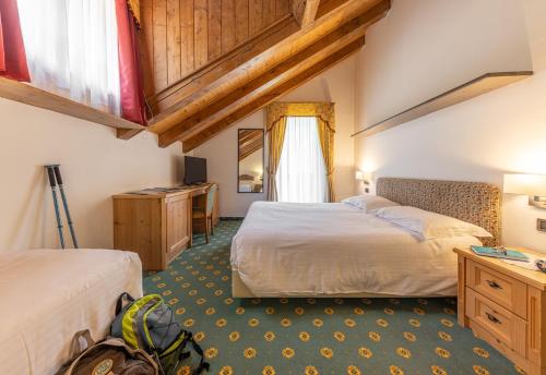 a hotel room with two beds and a desk at Hotel Plank in San Martino di Castrozza