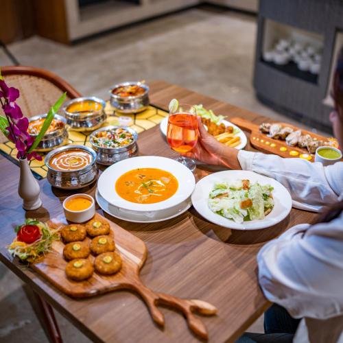 Una mesa de madera con platos de comida encima. en Regenta Inn Gurugram Sec-47 City Center, en Gurgaon