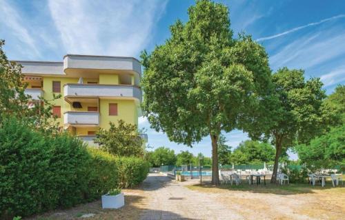 un edificio amarillo con árboles delante de él en La Dolce Vita - Apartment with shared pool and large terrace, en Lido delle Nazioni