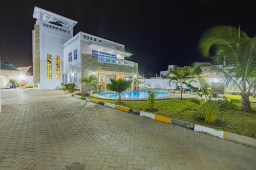 a large building with a swimming pool at night at Waiti homes in Diani Beach