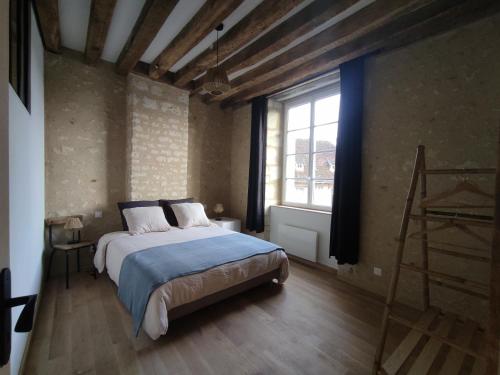 a bedroom with a bed and a large window at Gîte Littérature dans le Perche in Rémalard en Perche