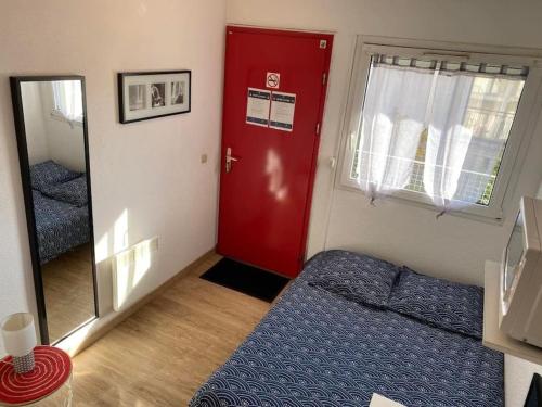 シャンブレー・レ・トゥールにあるStudio aménagé + parkingの赤いドア、ベッド、鏡が備わるお部屋