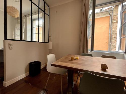 une salle à manger avec une table en bois et une fenêtre dans l'établissement Magnifique Appart - fameuse Rue piétonne MrJoffre, à Cahors