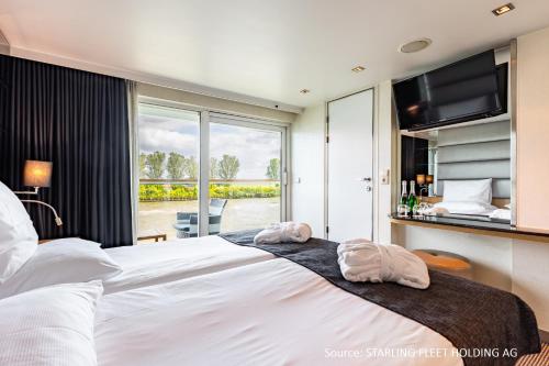 a bedroom with a large bed with two towels on it at KD Moment Premium Hotelship Köln in Cologne