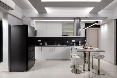 a kitchen with white cabinets and a table with stools at Rhodes Skyline Suite with out Door Jacuzzi Sea View A2 in Ixia