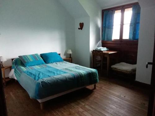 - une chambre avec un lit doté de draps bleus et une fenêtre dans l'établissement Chalet des Bruyères, à Saint-Jorioz