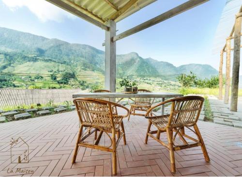 a table and chairs on a patio with mountains in the background at Sa Moc - La Maison House & Bungalow in Sa Pa