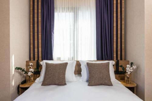 a bed with white sheets and pillows in front of a window at Ema Houses in Antalya