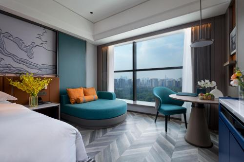 a hotel room with a bed and a chair and a window at Mehood Hotel Guangzhou Pazhou Convention and Exhibition Center in Guangzhou