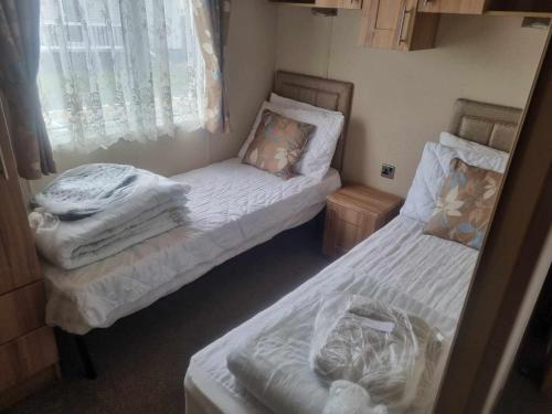 two beds in a small room with white sheets at PG144 on the Golden Palm Chapel St Leonards 3 bed deluxe in Chapel Saint Leonards