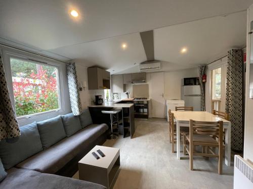 un salon avec un canapé et une table et une cuisine dans l'établissement Superb Mobilhome Ba302 - 3 bedrooms Siblu Bonne Anse La Palmyre, aux Mathes
