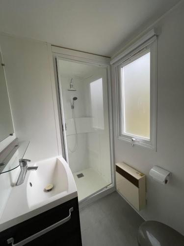 une salle de bain blanche avec une douche et un lavabo dans l'établissement Superb Mobilhome Ba302 - 3 bedrooms Siblu Bonne Anse La Palmyre, aux Mathes