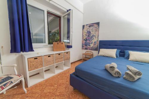 1 dormitorio con 2 camas azules y ventana en Dea Rooms, en Castellabate