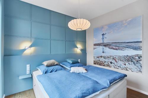 a blue bedroom with a bed with a painting on the wall at Apartamenty Świnoujście -Seaside Garden 52 in Świnoujście