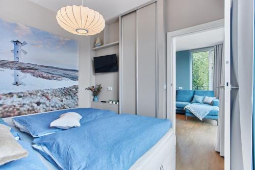 a bedroom with a blue bed and a couch at Apartamenty Świnoujście -Seaside Garden 52 in Świnoujście