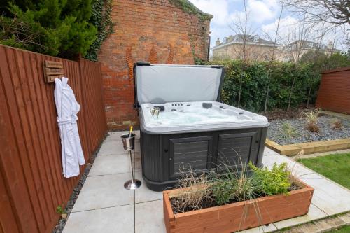 uma banheira sentada num jardim ao lado de uma cerca em Elliot Oliver - Superior 6 Bedroom House in Cheltenham With Hot Tub & Log Burner em Cheltenham