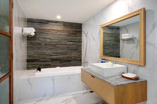 a bathroom with a sink and a tub and a mirror at D'Sawah Villa Umalas in Canggu